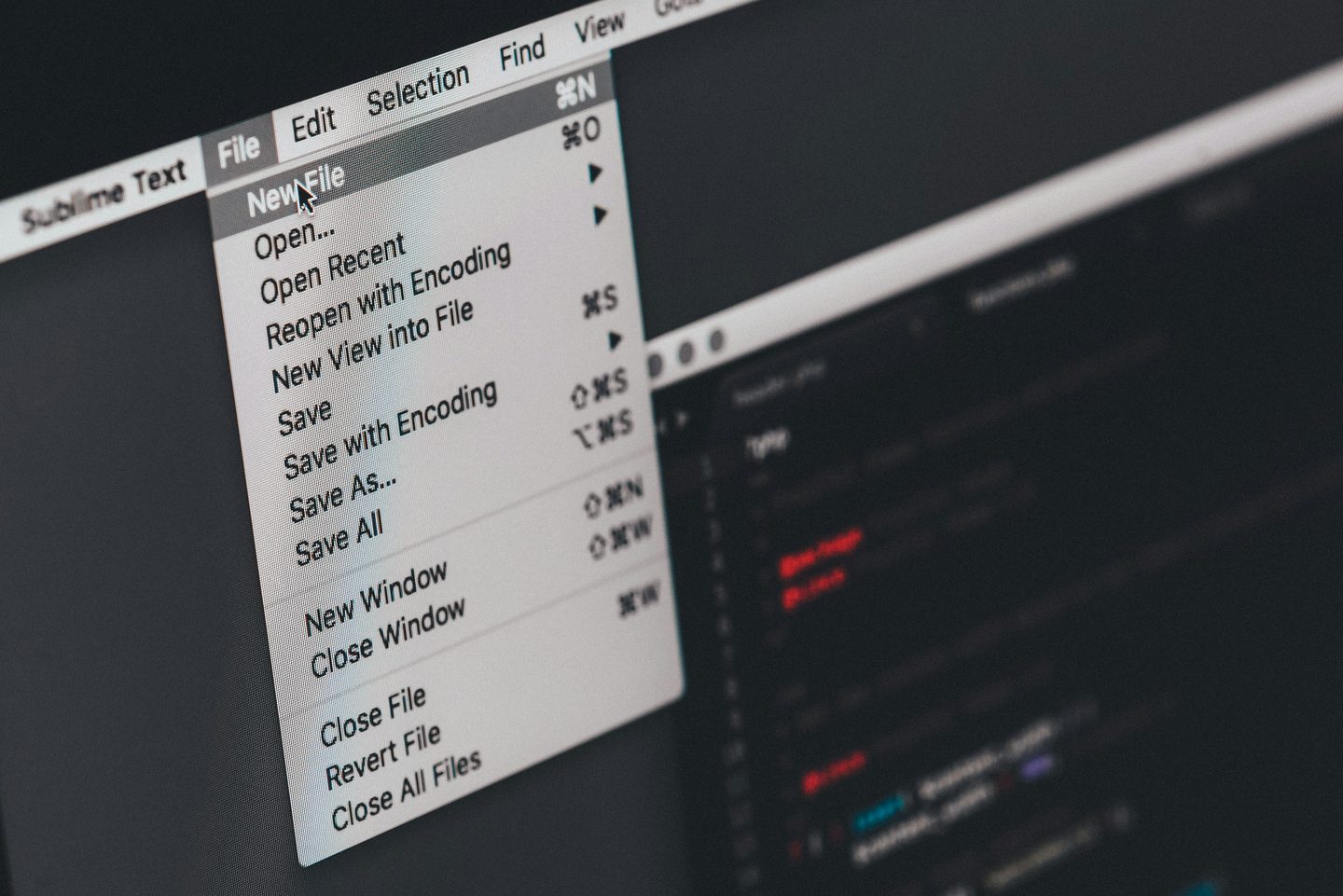 Gros plan en noir et blanc sur un écran d'ordinateur : le menu « File » d'un éditeur de texte est ouvert sur les commandes « New File », « Open… » et « Save ».