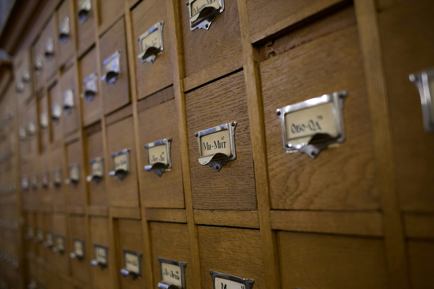 Rangées de tiroirs en bois d'un fichier de bibliothèque, munis de porte-étiquettes métalliques en caractères cyrilliques.