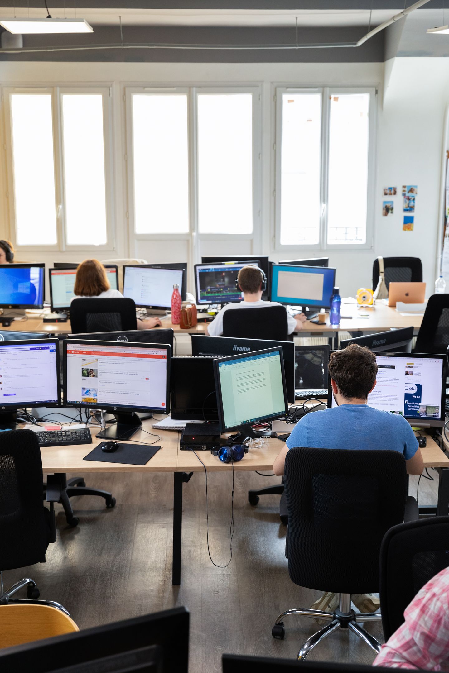 La rédaction de 6Médias : des journalistes, vus de dos, travaillent sur plusieurs écrans.