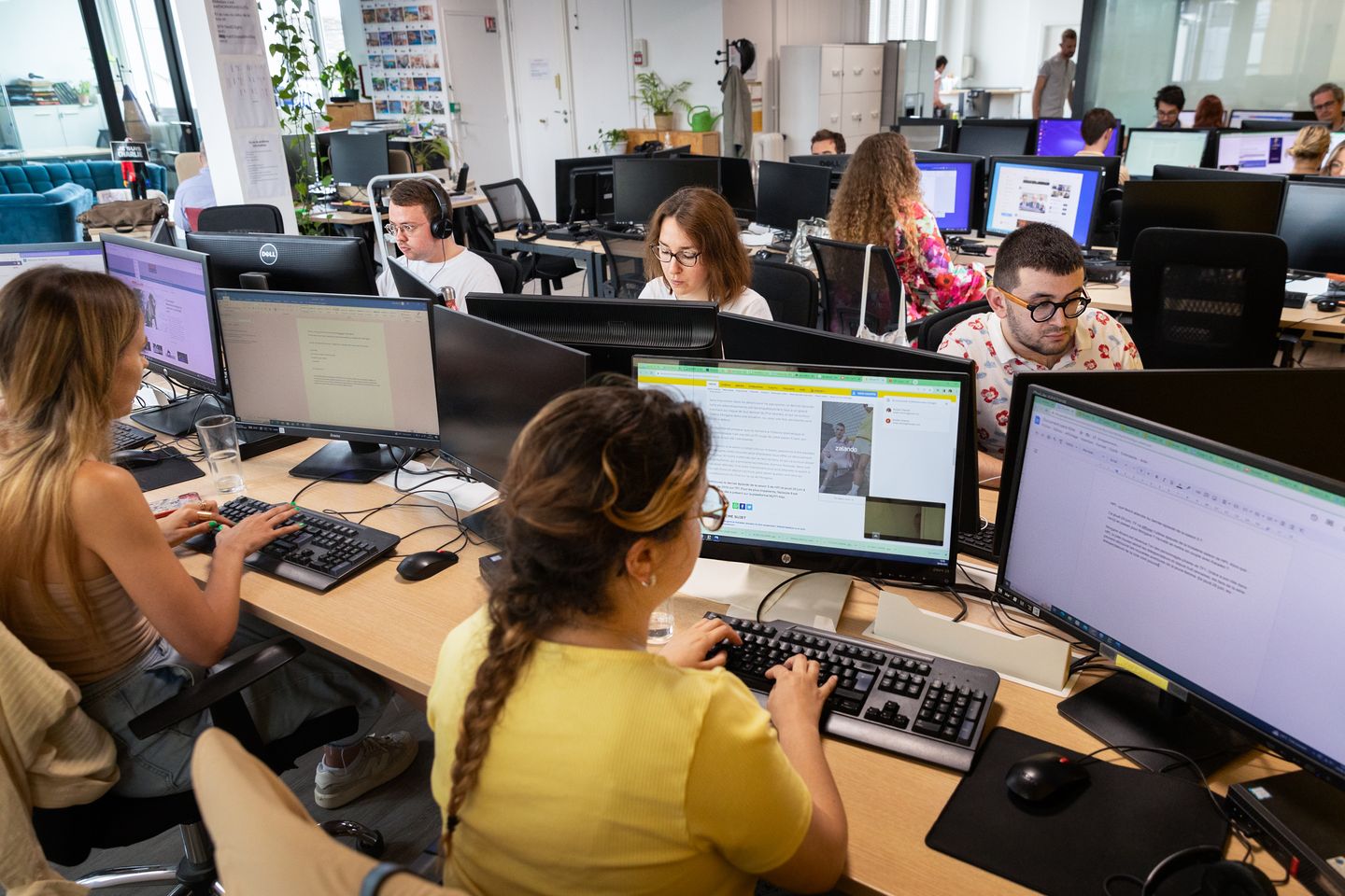 La salle de rédaction de 6Médias à Paris : des journalistes écrivent face à leurs écrans, dans un grand espace de travail lumineux.